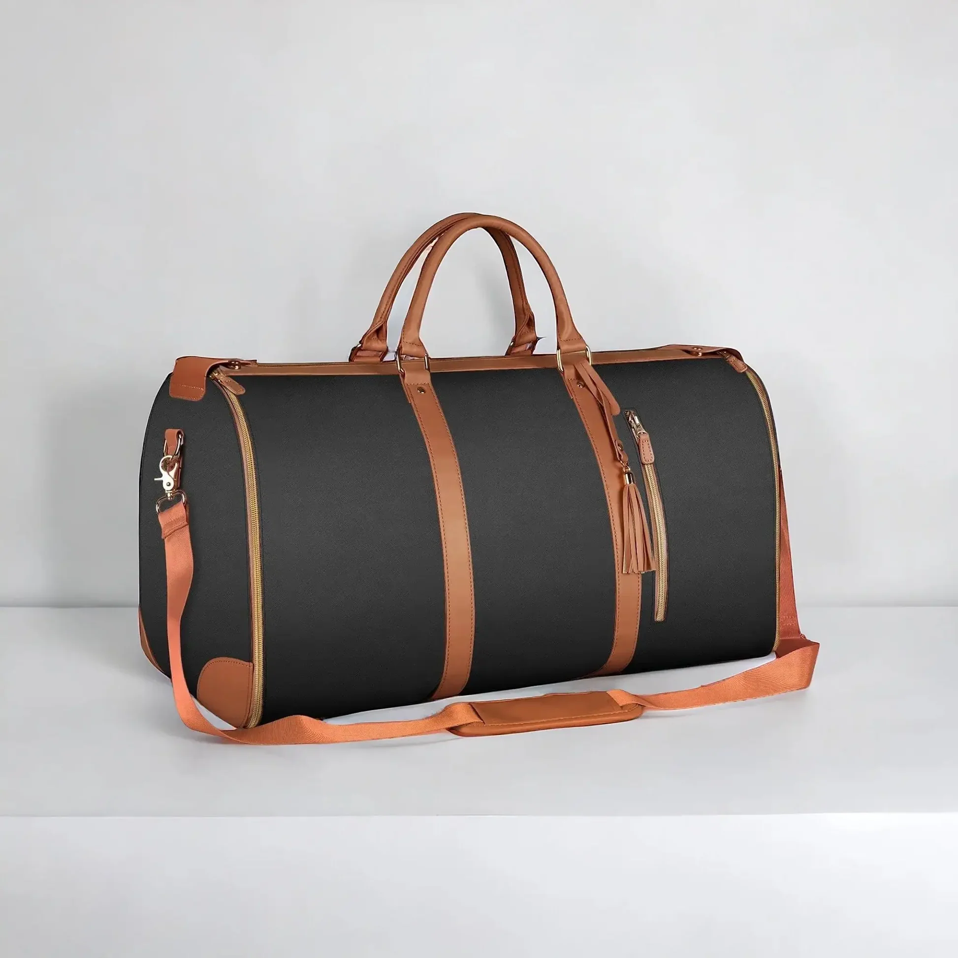 Svart reisebag med brune detaljer og gyldne glidelåser vises stående på en hvit flate, med en enkel bakgrunn.