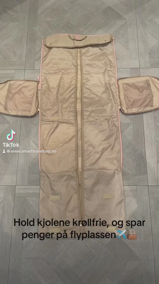 Beige klespose med glidelås og lommer, lagt flat på et gulv med grått parkettmønster. Tekst på bildet markedsfører funksjonaliteten for å holde klærne krøllfrie.